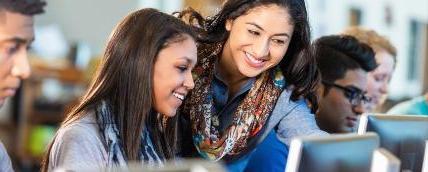 A teacher guides a student through a computer project.